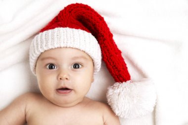 Noel Baba şapkası yatakta yatan erkek bebek.