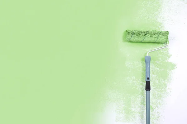 Paint roller next to the green wall. — Stock Photo, Image
