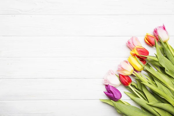 Tulipanes coloridos sobre fondo de madera blanco . — Foto de Stock