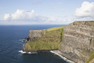 Büyüleyici anne uçurumları, mavi deniz ve berrak gökyüzü, yeşil çimenler.