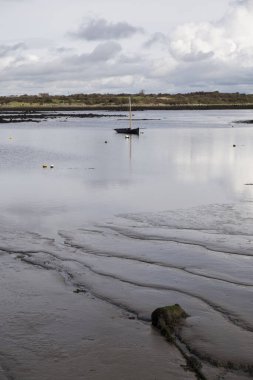 İrlanda koyunda yelkensiz küçük ahşap bir teknenin manzarası, sakin karanlık su, bulutlu bir gün.