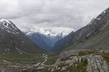Kuzeyli dağlık arazi, karlı zirveleri olan yüksek dağlar, bulutlu, alp manzarası
