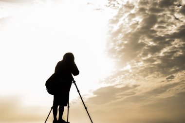 Gün batımında fotoğraf çeken bir fotoğrafçının silueti.