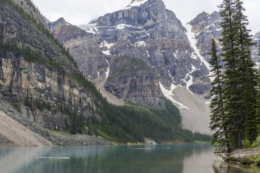 Turkuaz su gölü, ormanın ortasında, yüksek ağaçlar ve büyük dağlarla Kanada 'da yaz boyunca.