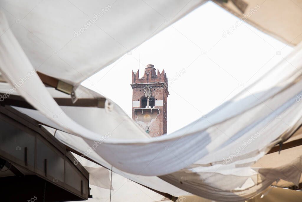 we can see part of the tower of an old building among the white fabrics that adorn the streets of the town