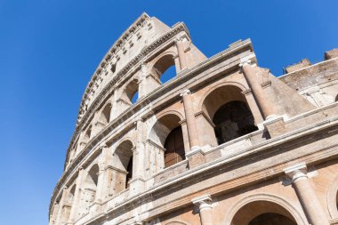 Kolezyum veya Flavian amfitiyatrosu, Roma, İtalya. Büyük yarı dairesel pencereli taştan yapılmış, çok iyi durumda bir Roma inşaatının parçası. Mavi gökyüzü berraktır.