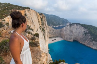 Yunanistan 'ın Zakynthos adasındaki ünlü gemi enkazı Navagio' nun nefes kesici manzarasının tadını çıkaran çekici bir kadın gezgin.