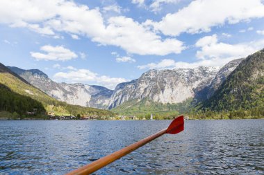 Tahta kürek, dağlar arasında göl, arka planda Avusturya 'da ahşap evleri olan küçük bir kasaba.