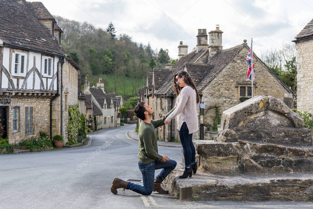 Petition for marriage, the man is kneeling asking the woman to marry in the square of a town in the south of England called Castle Combe