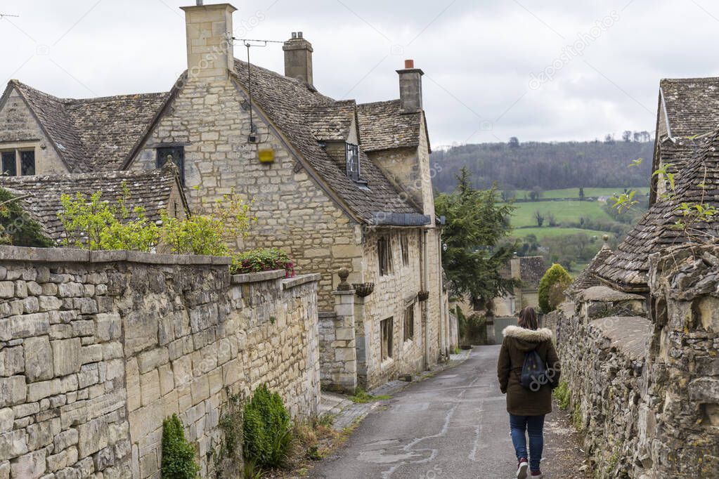 woman walking through an english town with stone houses in a rural area