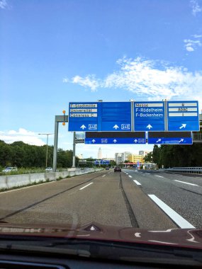 Frankfurt am Main, Almanya - 20 Temmuz 2017: Otoyol üzerindeki büyük işaretler araba Frankfurt şehrine girerken, uzaktaki gökdelenlerle birlikte