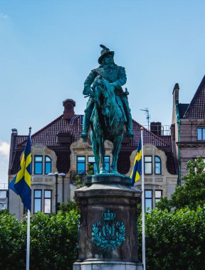 Malmö, İsveç - 11 Temmuz 2018: Kasaba meydanında büyük bir heykel gururla duruyor. Arka planda İsveç bayrakları, vatansever bir izlenim veriyor..