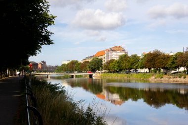 Ağaçlar ve binalar sıcak bir yaz sabahı İsveç 'in Malmö kanallarında yansımalar yapıyor.
