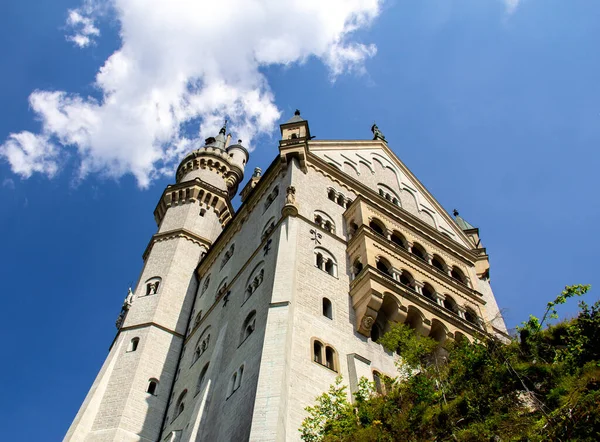 Hohenschwangau, Gemany - 20 Temmuz 2018: Sıcak bir yaz gününde açık mavi gökyüzüne yükselirken Neuschwanstein kalesinin ön cephesi ve kulesinin alçak açılı görüntüsü