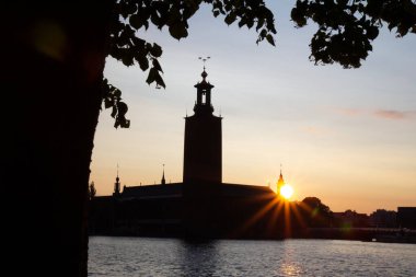Stockholm Belediye Binası 'nın arkasında güneş batıyor ve İsveç' in Stockholm şehrinde sıcak bir yaz gününde sular....