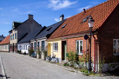 Ystad, İsveç - 23 Haziran 2019: Eski kentte küçük evler, güller ve bisikletlerle çevrili boş bir kaldırım taşlı sokak