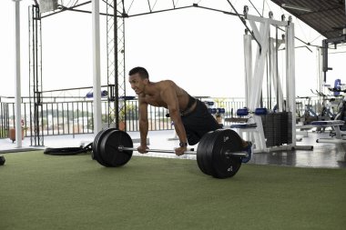 Gülümseyen adam spor salonunda egzersiz yapıyor.