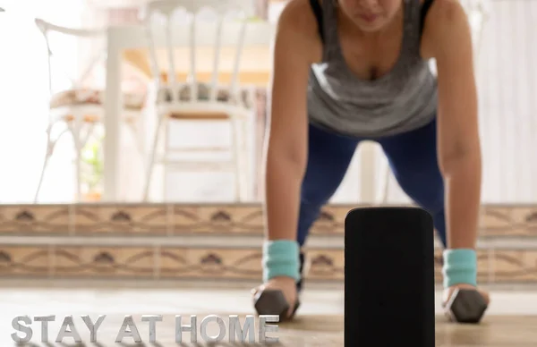 woman practicing sport at home with dumbbells in video conference with cell phone concept stay at home