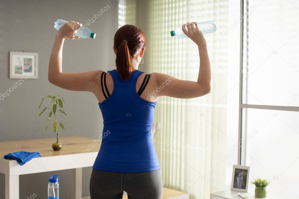 woman in running of the bulls exercising with homemade items in the dining room showing her back
