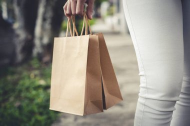 Elinde kağıt torbalarla sokakta yürüyen biri.