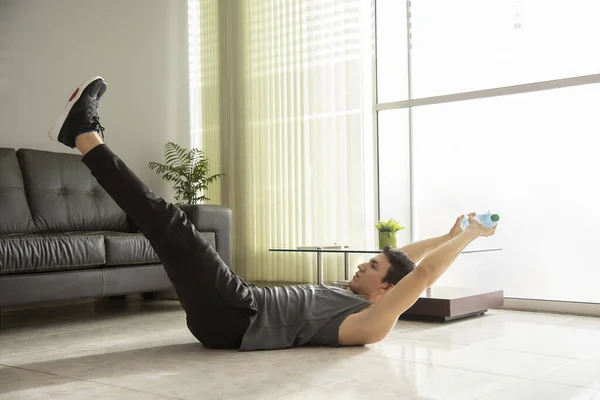 man doing leg lift on the floor with bottle of water, concept exercise at home