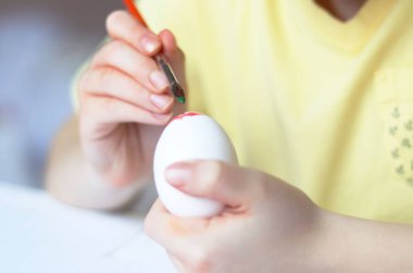 Paskalya bayramında çocuk boyayla yumurta boyuyor.