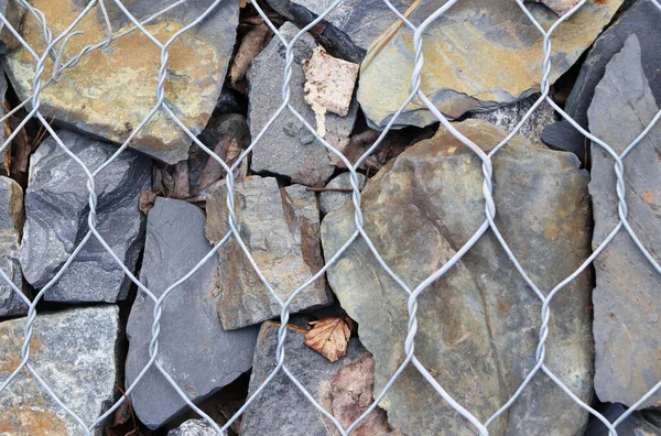 stone fence in a steel mesh. background of stones