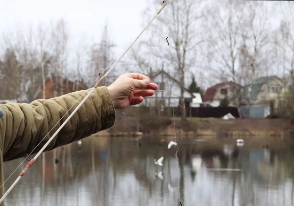 Fisherman is fishing on the pond. Fishing rod with a worm.