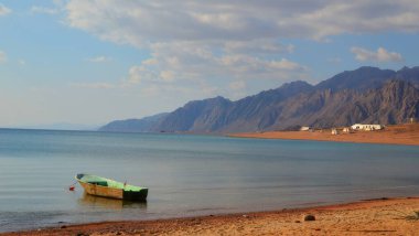 Dağın arka planında kıyıya yakın bir tekne.