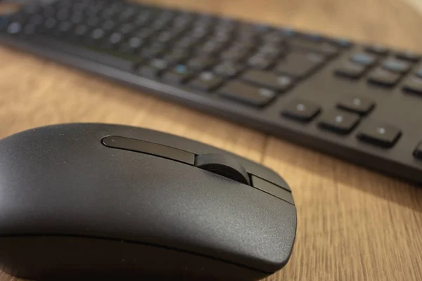 Wireless mouse and keyboard set on top of a wooden office desk, on a workstation