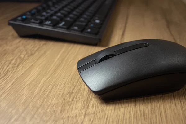 Wireless mouse and keyboard set on top of a wooden office desk, on a workstation