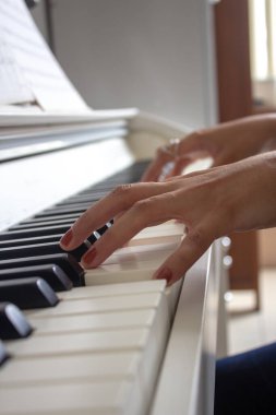 Beyaz elektrikli piyanosuyla ders çalışan bir kadın.