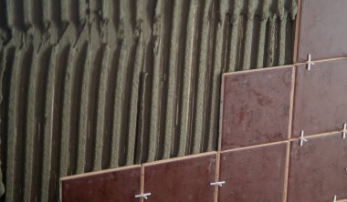 Usta fayansı duvara koyar. Seçici odak.