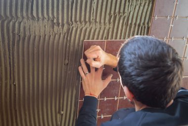 Usta fayansı duvara koyar. Seçici odak.