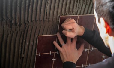 Usta fayansı duvara koyar. Seçici odak.