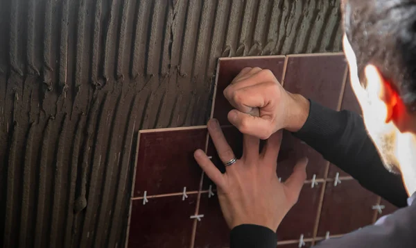 The master puts the tile on the wall. Selective focus.