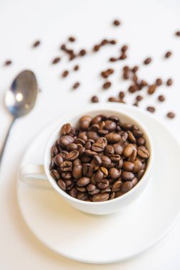 Beyaz arka planda beyaz fincan ve kahve çekirdekleri. Seçici odak.
