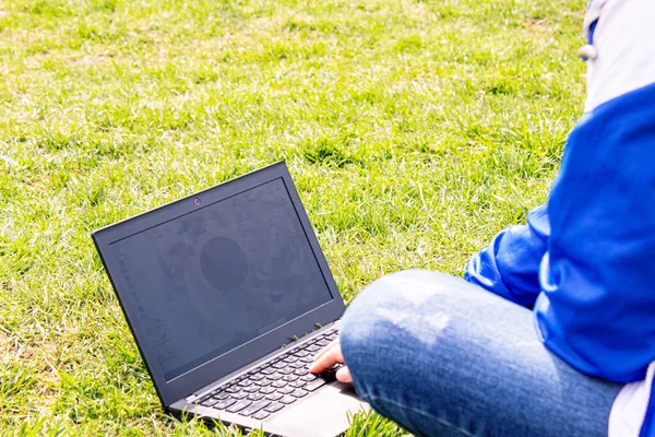 girl with a laptop on the grass. distance lesson. online lessons. selective focus