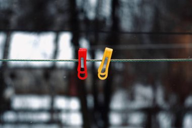 Sokakta kışın çamaşır ipinde kırmızı ve sarı mandal.