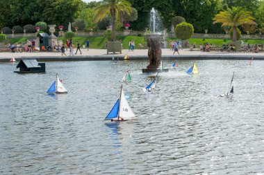 Lüksemburg Parkı 'ndaki bir çeşmenin etrafındaki havuzda çok renkli tekneler yüzüyor. Paris mi? Fransa.