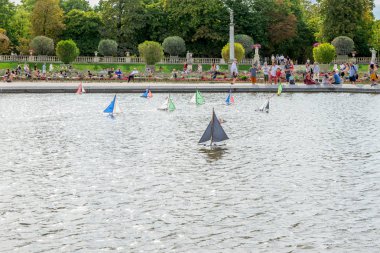 Lüksemburg Parkı 'ndaki bir çeşmenin etrafındaki havuzda çok renkli tekneler yüzüyor. Paris mi? Fransa.