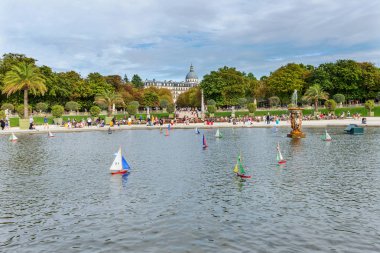 Lüksemburg Parkı 'ndaki bir çeşmenin etrafındaki havuzda çok renkli tekneler yüzüyor. Paris mi? Fransa.