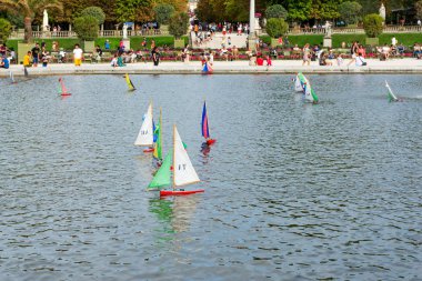 Lüksemburg Parkı 'ndaki bir çeşmenin etrafındaki havuzda çok renkli tekneler yüzüyor. Paris mi? Fransa.