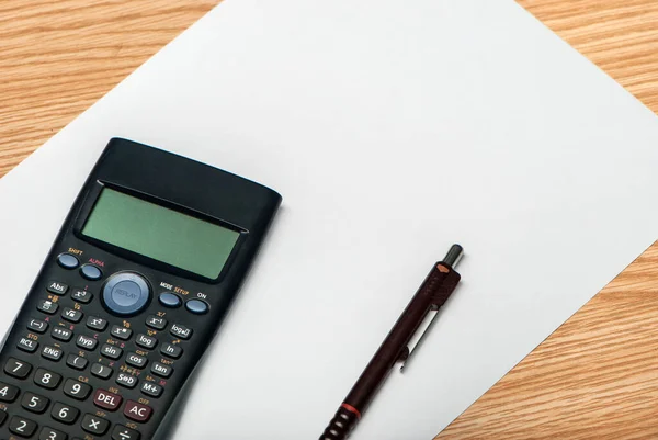 Industrial calculator with white paper on wooden table, ready to study.