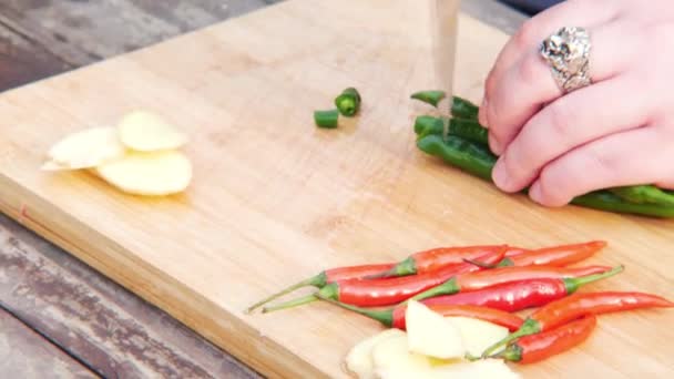 新鮮なハーブと素朴な木のテーブルの上の生野菜の盛り合わせに囲まれたナイフと木製のまな板で手の生活ビュー — ストック動画