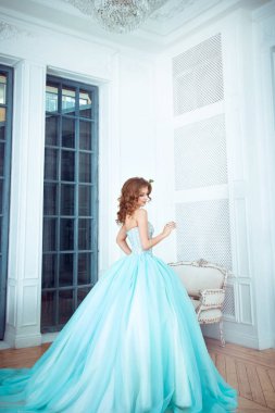 Güzel genç kız uzun, muhteşem turkuaz elbiseli prenses bir ışık kalesinde duruyor. Peri masalı moda fotoğraf çekimi Külkedisi. Güzel oda.. 