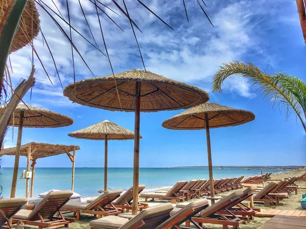 Tumbonas y sombrillas de paja en la playa —  Fotos de Stock