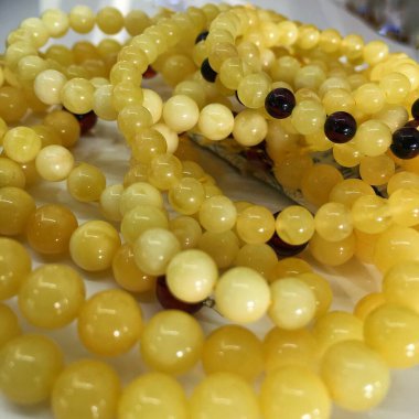 Sarı ve beyaz Baltık kehribarından bir sürü boncuk. Kuyumcunun dekorasyonu için doğal kehribar arka planı.