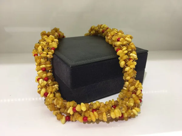 Perles en ambre perlé à la main reposent sur une boîte à bijoux cadeau sombre . — Photo
