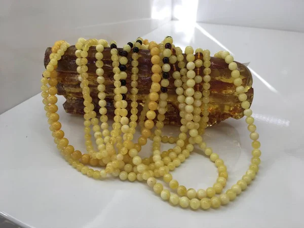 Un sacco di perline bianche ambra baltica si trovano su un pezzo di ambra . — Foto Stock